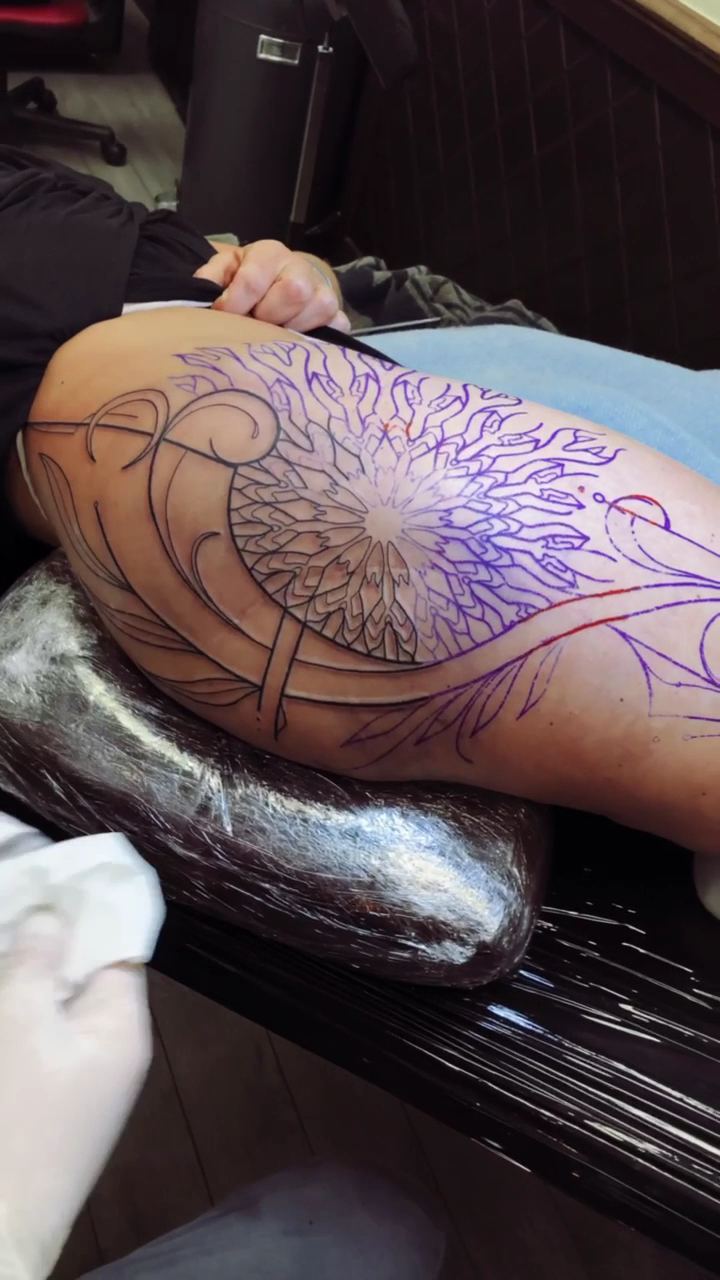 Mandala ant šlaunies tatuiravimo metu